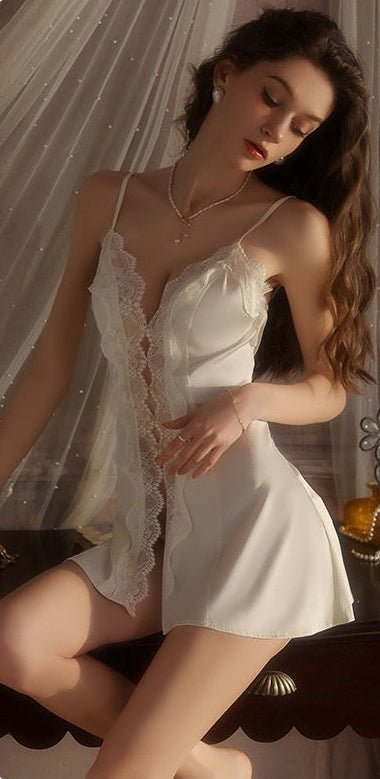 Woman wearing a white nightdress with lace details in a softly lit room.